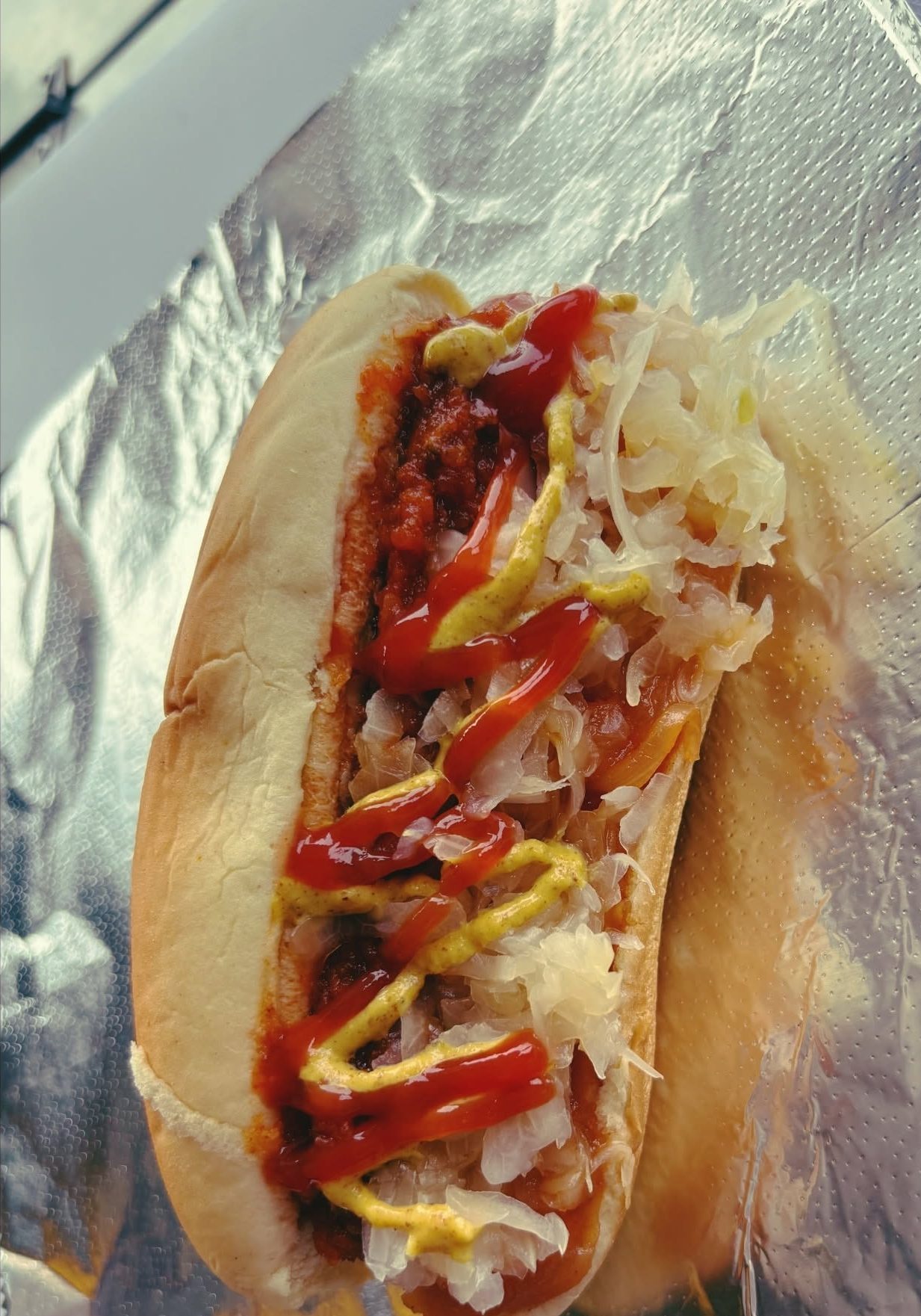 A loaded dirty dog piled with chili, sauerkraut, ketchup and mustard