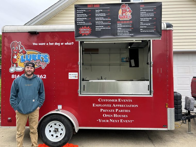 The Luke’s Dirty Dogs trailer parked and set up to serve, menu board lit up top